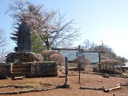 大きな石碑と右奥にアンテナの見える山頂部